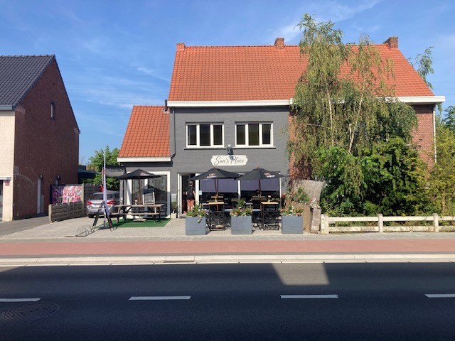 Vooraanzicht van San's Place broodjeszaak aan de Handelslei 22 in Sint-Job-in-'t-Goor, met terras en parasols